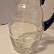 Glass carafe with wavy body and blue handle