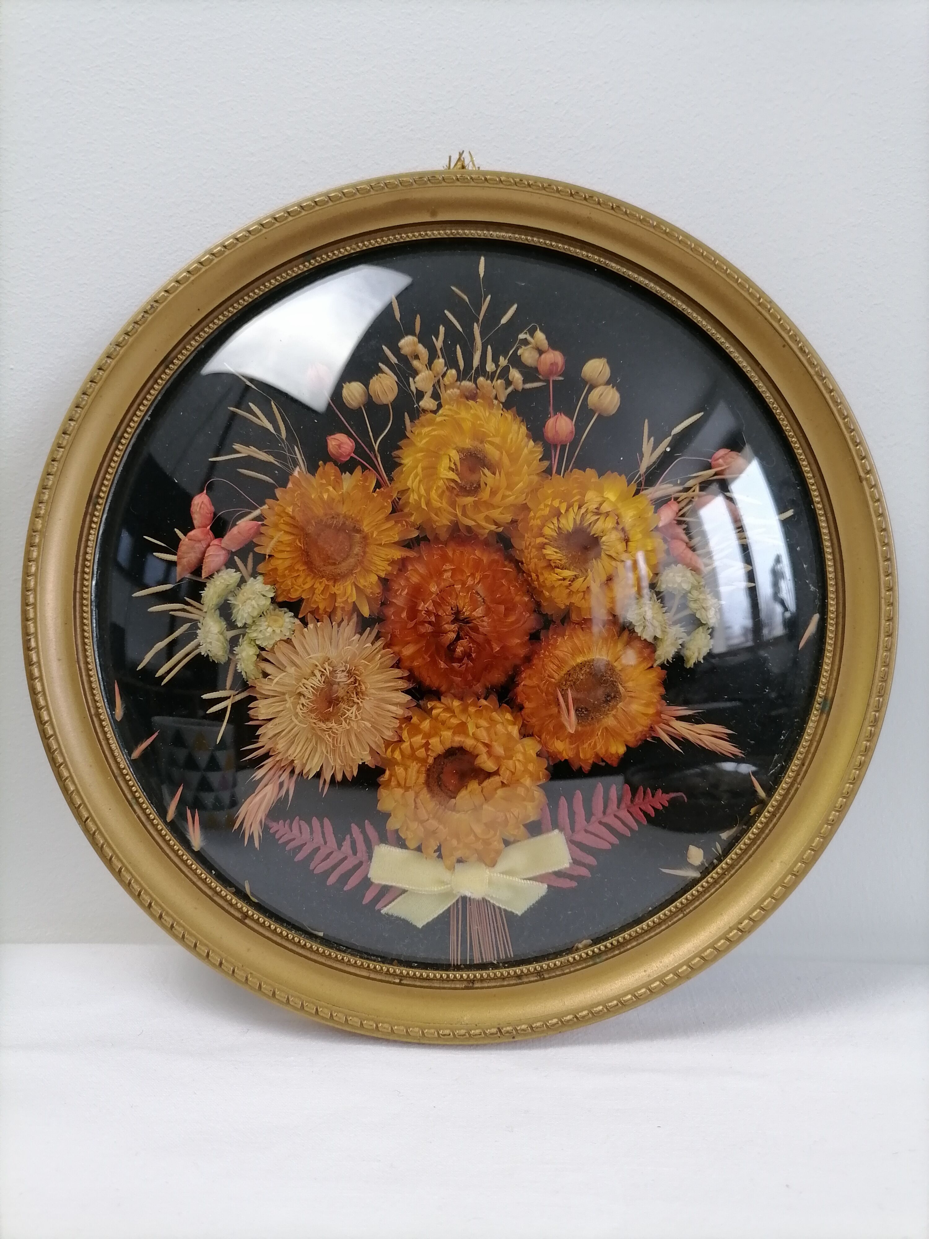Dried flowers under curved glass frame