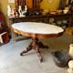 Table with a carved wooden frame and grey marble top on wheels, measuring 130 x 82 cm.