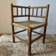 Antique corner chair by the fire with turned wood and straw seat.