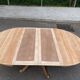 Round dining table with a central pedestal, extendable, stripped in solid walnut with 2 extensions.