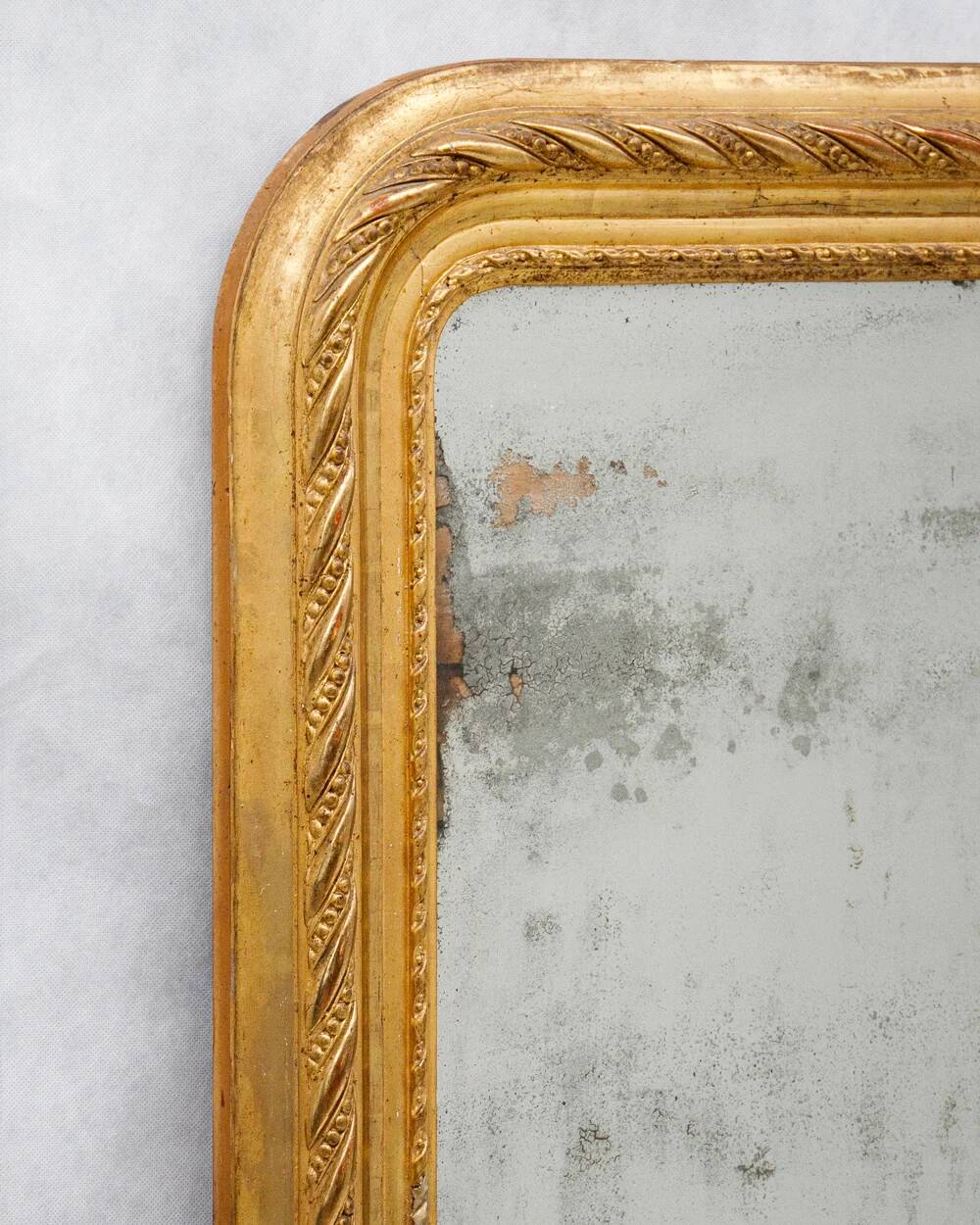19th-century patinated mirror with a ribbon-style frame