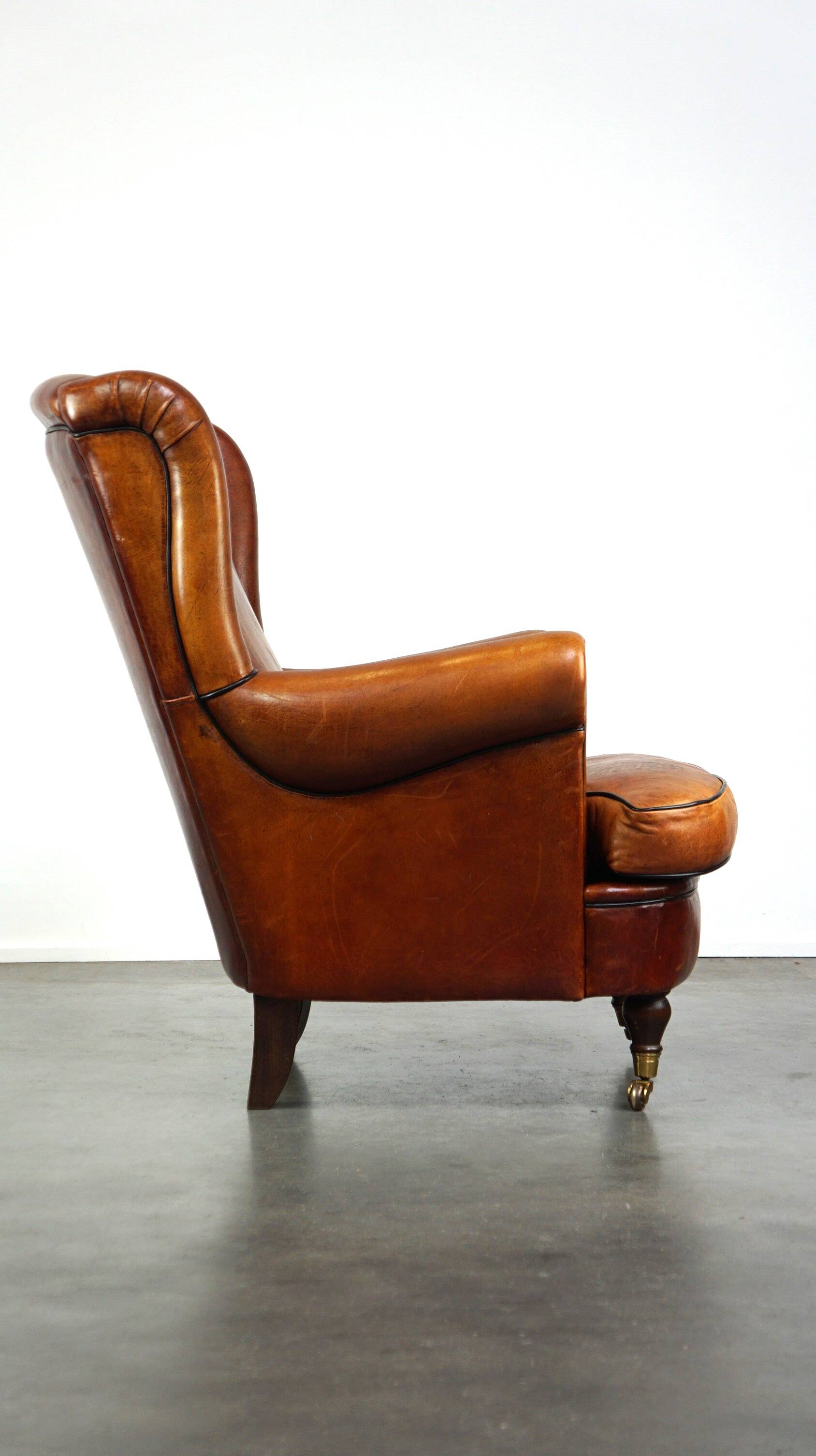 Subtle sheepskin wing chair in good condition on brass front wheels
