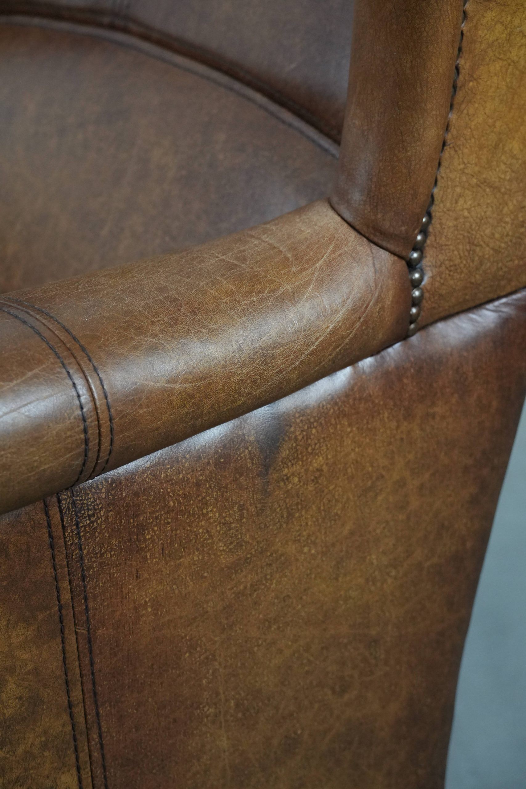 Cognac-coloured wingback armchair in English style made of cowhide leather