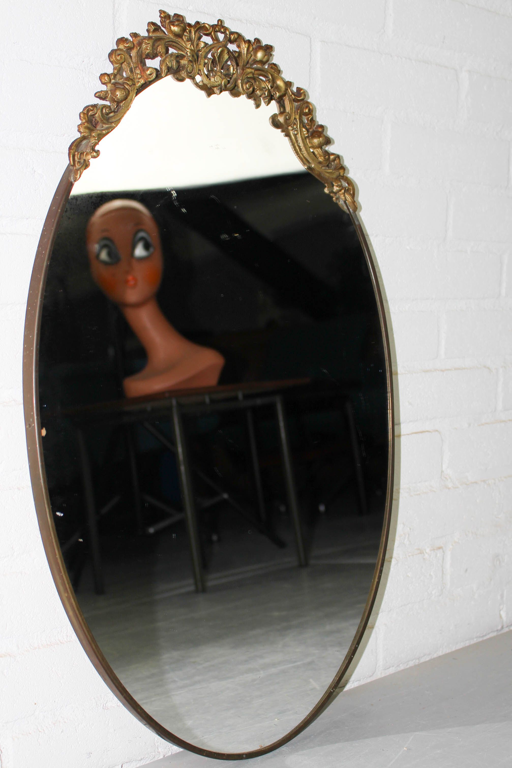 Miroir mural ovale antique dans un cadre en laiton avec ornement supérieur