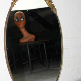 Miroir mural ovale antique dans un cadre en laiton avec ornement supérieur