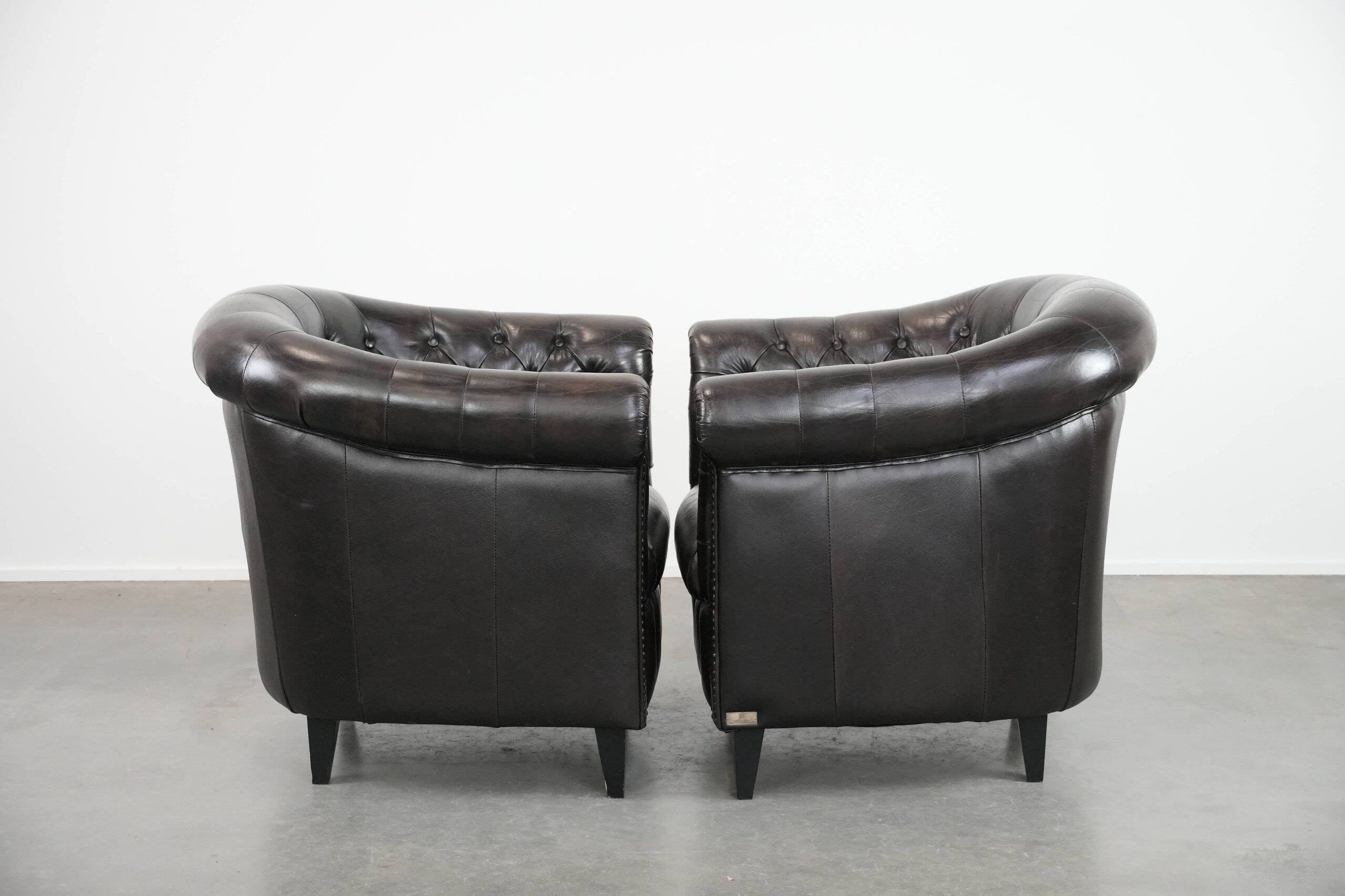 Ensemble de deux luxueux fauteuils club Chesterfield en cuir de vachette noir.