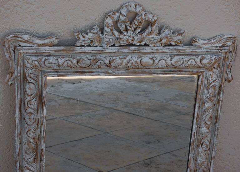 Chic and stylish antique mirror with carved wooden frame in whitewashed
