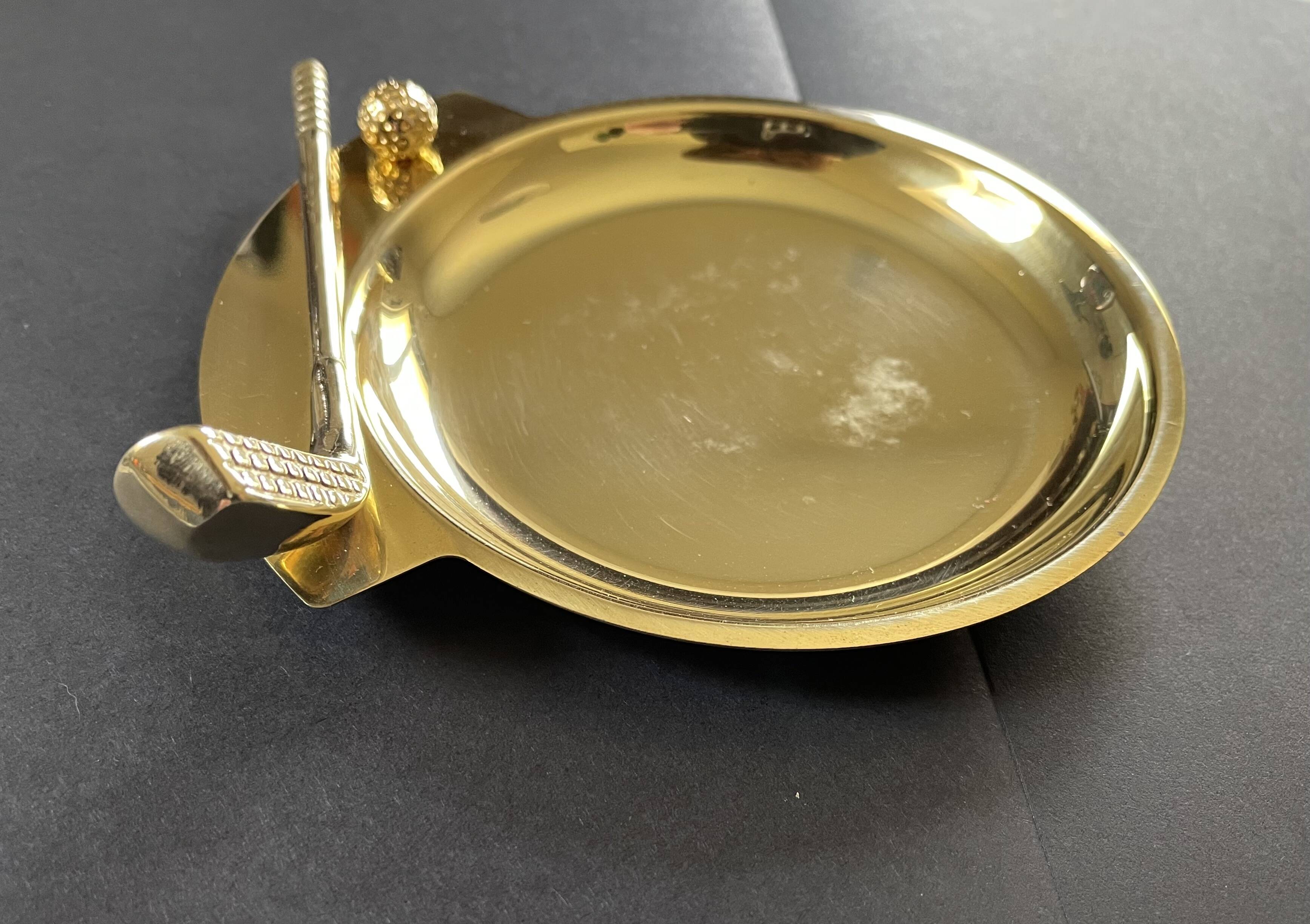 Round brass pocket tray with club and golf ball decoration.