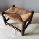 Antique wooden turned spool footrest with straw.