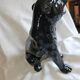Statue of a roaring panther/leopard sitting in black glazed ceramic.
