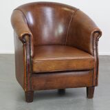 Subtle, neat sheepskin leather club armchair with a fixed seat cushion in a deep, dark cognac color