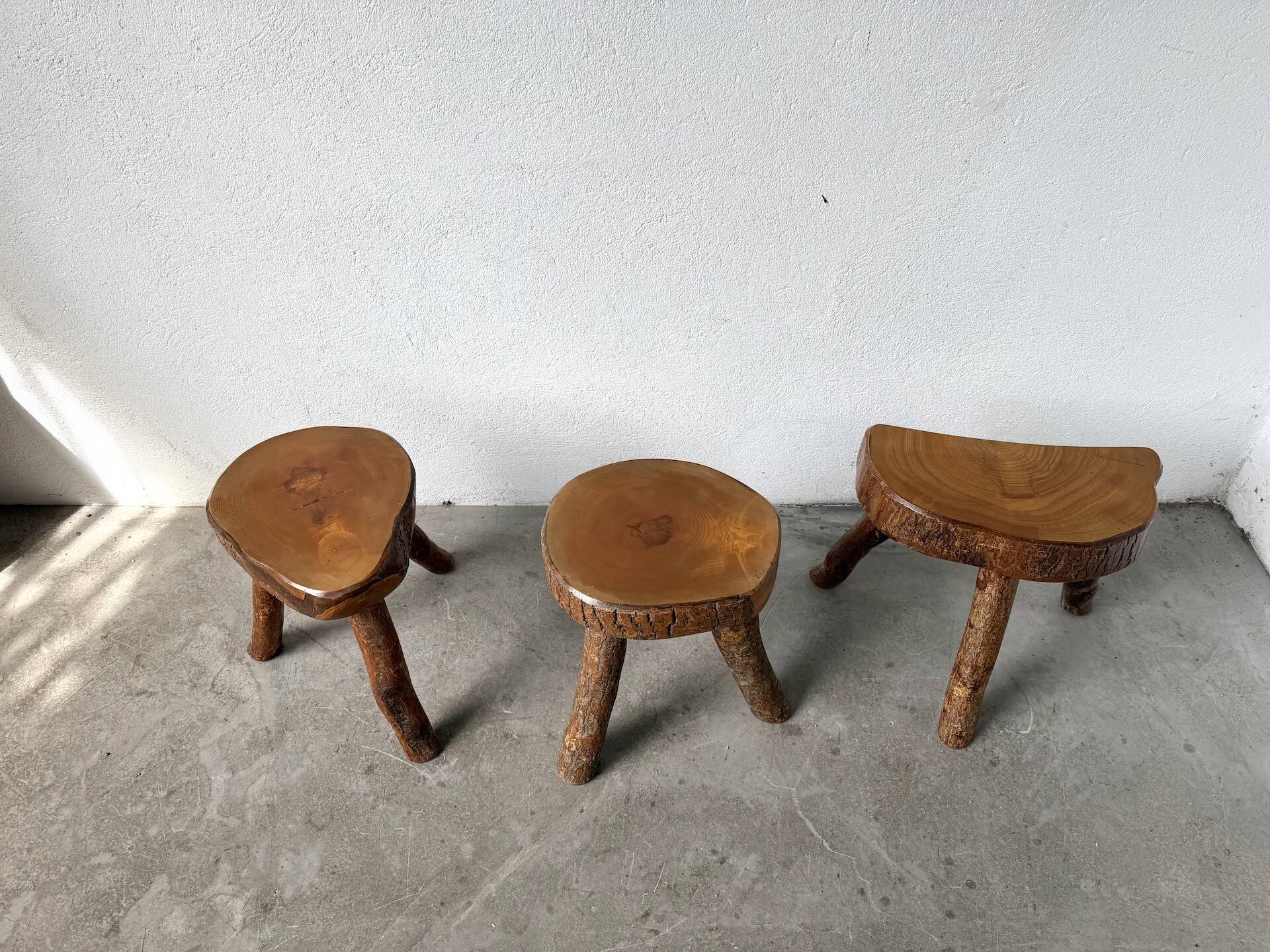 Set of three rustic solid wood tripod stools.