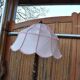 Brown carved wooden floor lamp with a pale pink shade and integrated shelf.