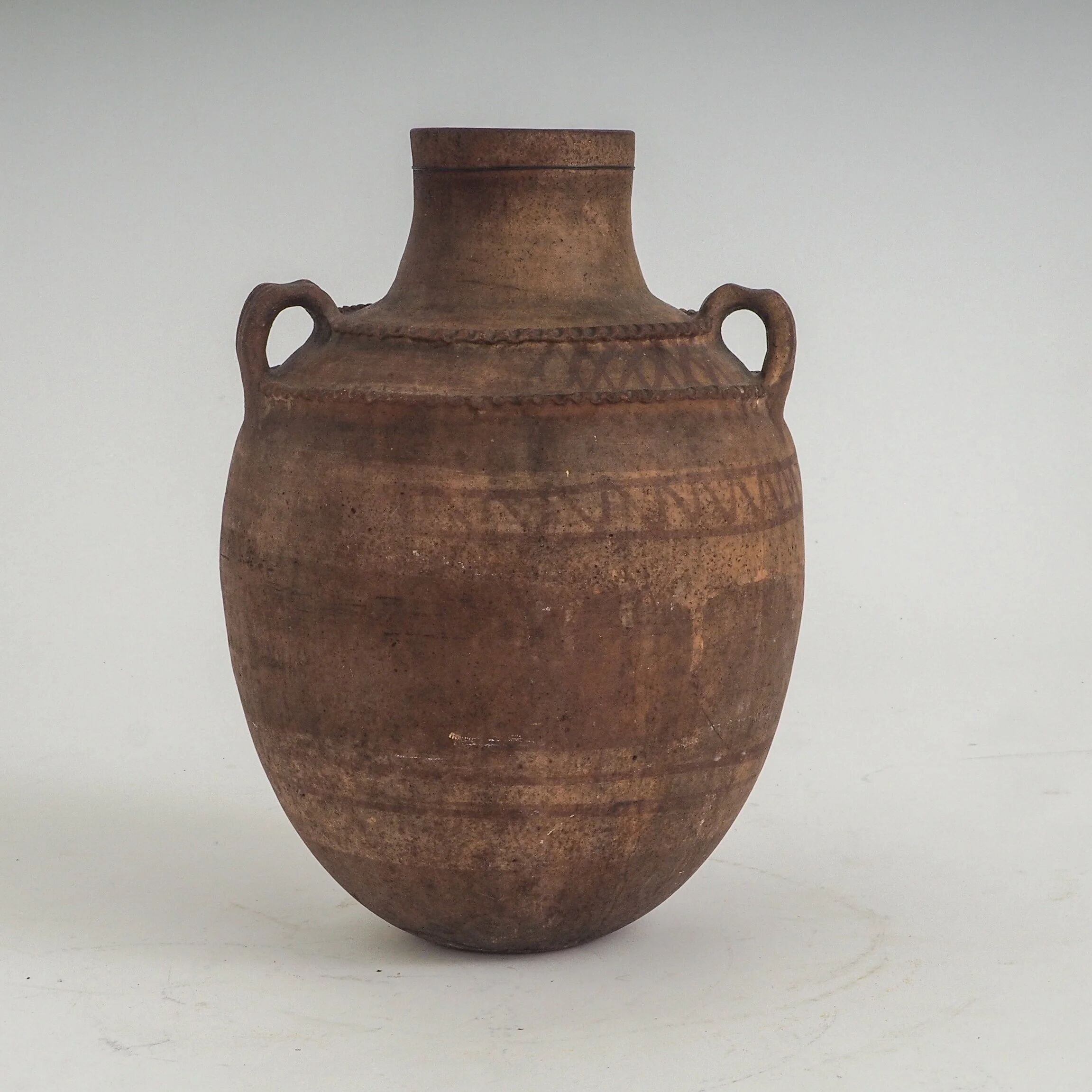 Vaisseau en terre cuite primitive avec des détails géométriques peints à la main.