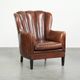 Fauteuil en peau de mouton confortable au design unique, fini avec un passepoil noir.