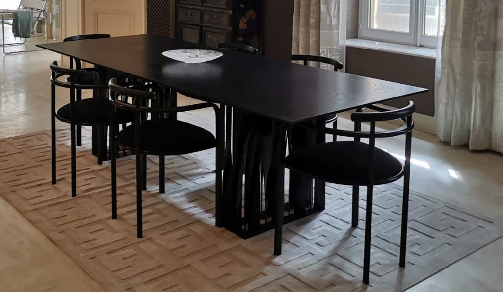 Black dining room table, wooden, rectangle with upholstered chairs.