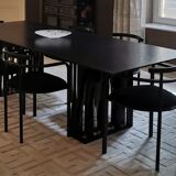 Table de salle à manger noire, en bois, rectangle avec chaises rembourrées.