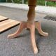 Large extendable round dining table stripped in solid cherry wood with a central leg.