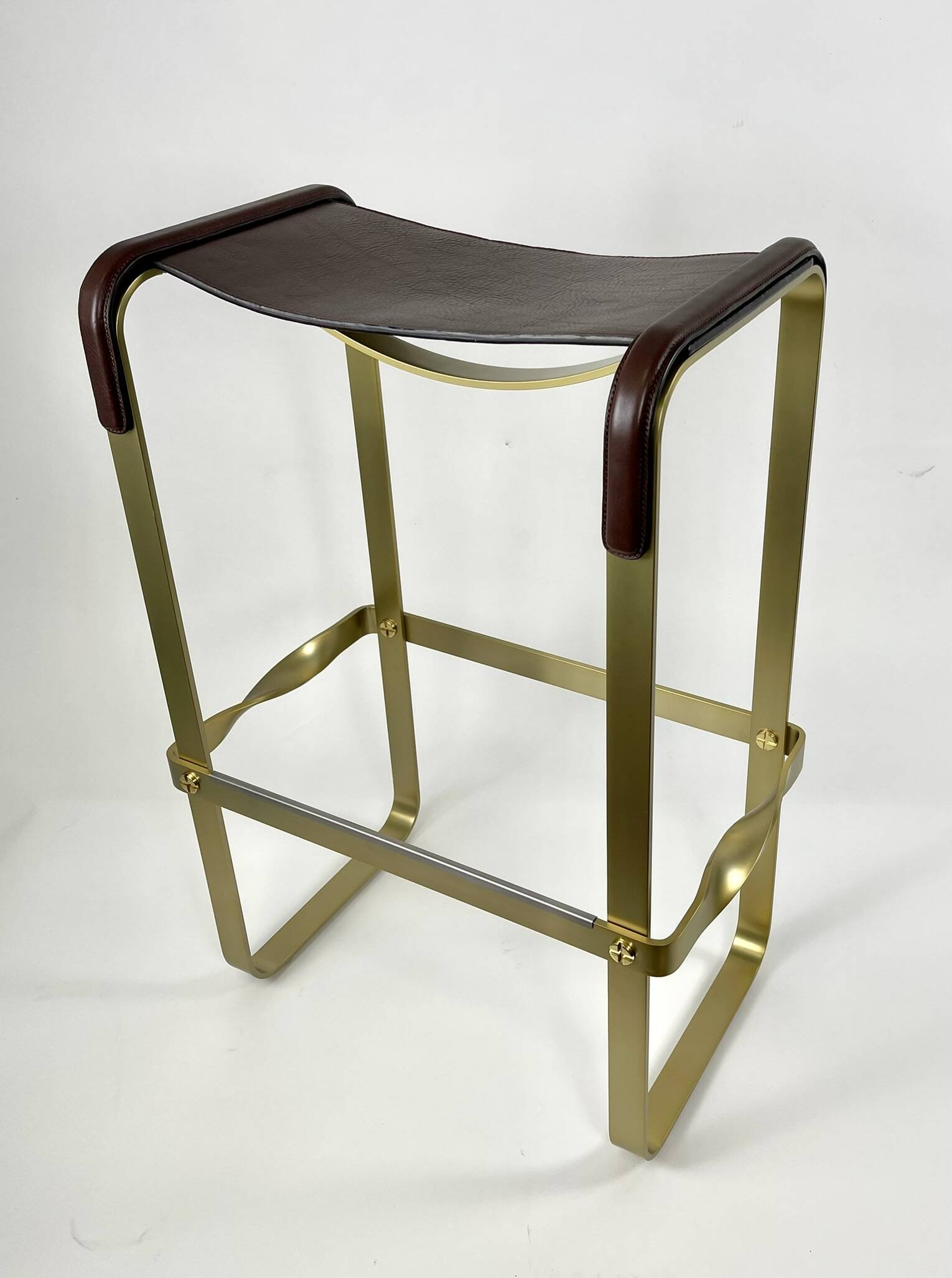 Bar stool in aged brass and brown leather.