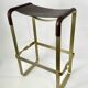 Bar stool in aged brass and brown leather.