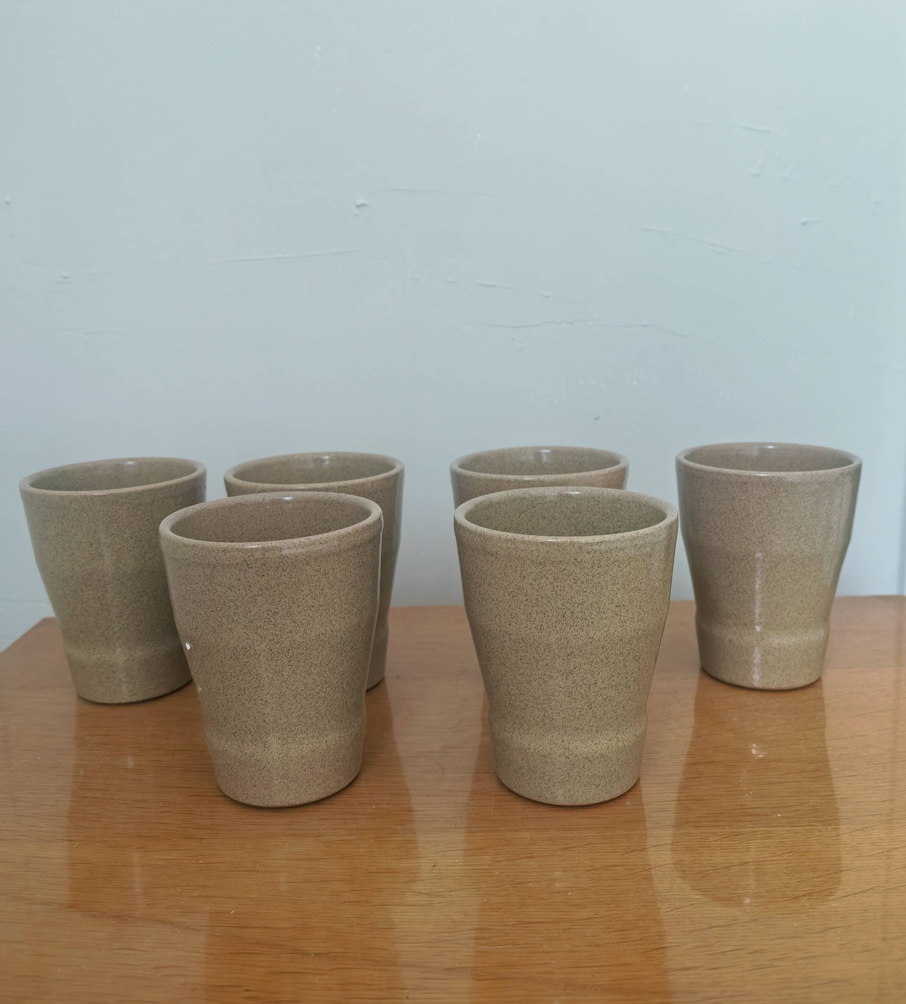 Set of 6 stoneware cups signed Cermer. Beige speckled, matte granular finish.
