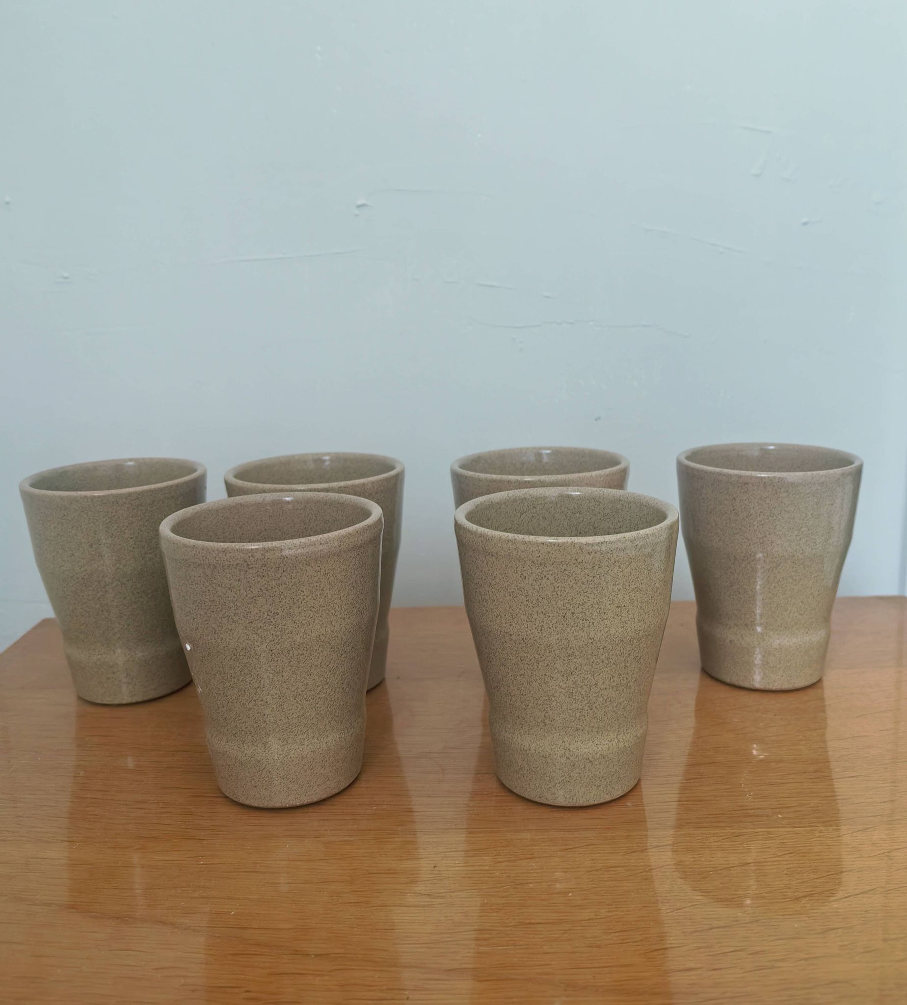 Set of 6 stoneware cups signed Cermer. Beige speckled, matte granular finish.