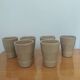 Set of 6 stoneware cups signed Cermer. Beige speckled, matte granular finish.