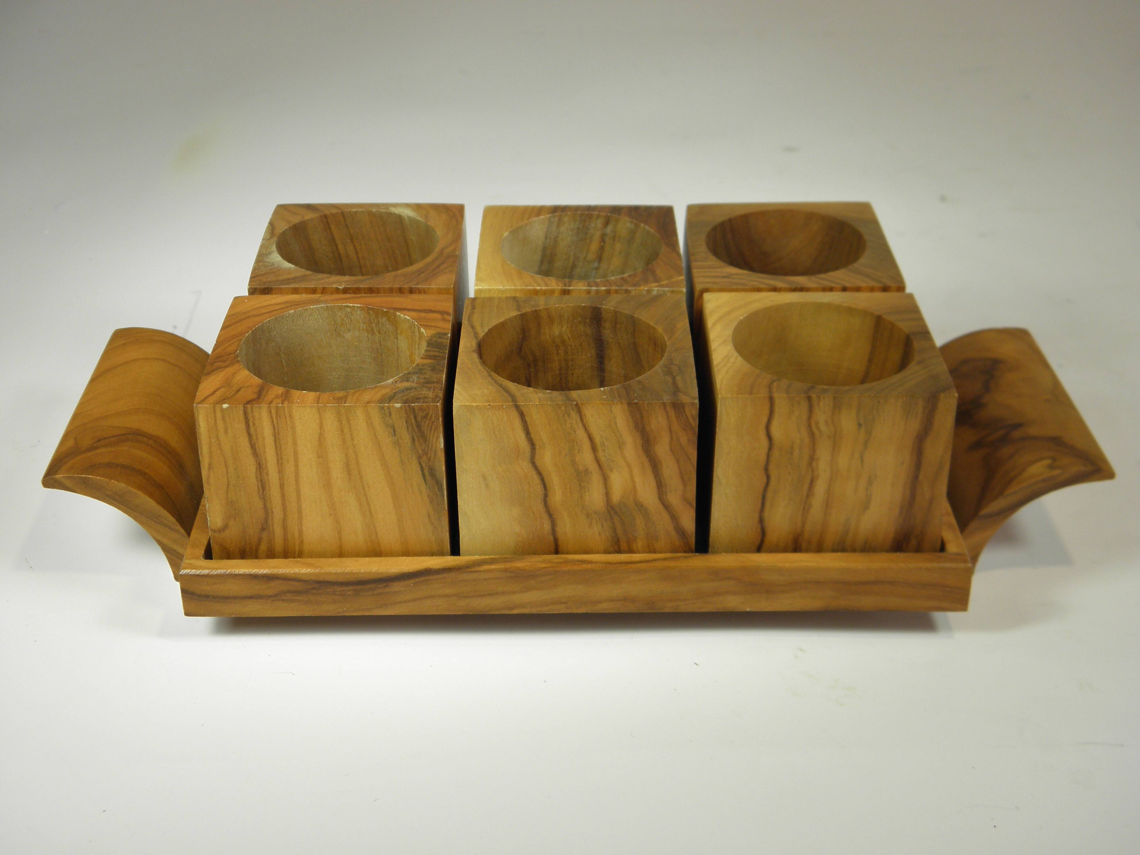 Six egg cups on a wooden tray.