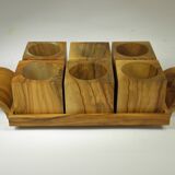Six egg cups on a wooden tray.