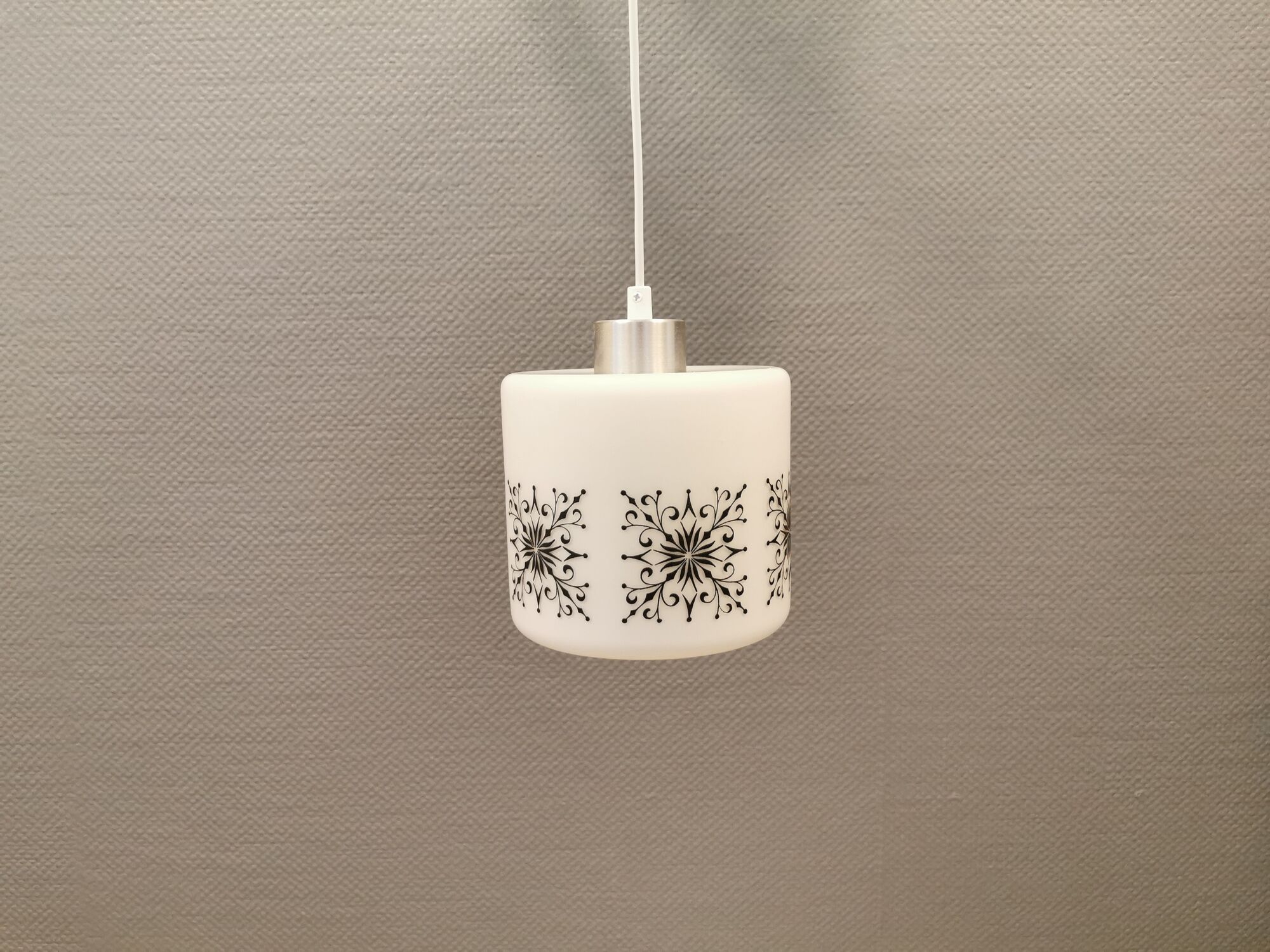 Scandinavian hanging lamp in white glass with inlayed black motifs.