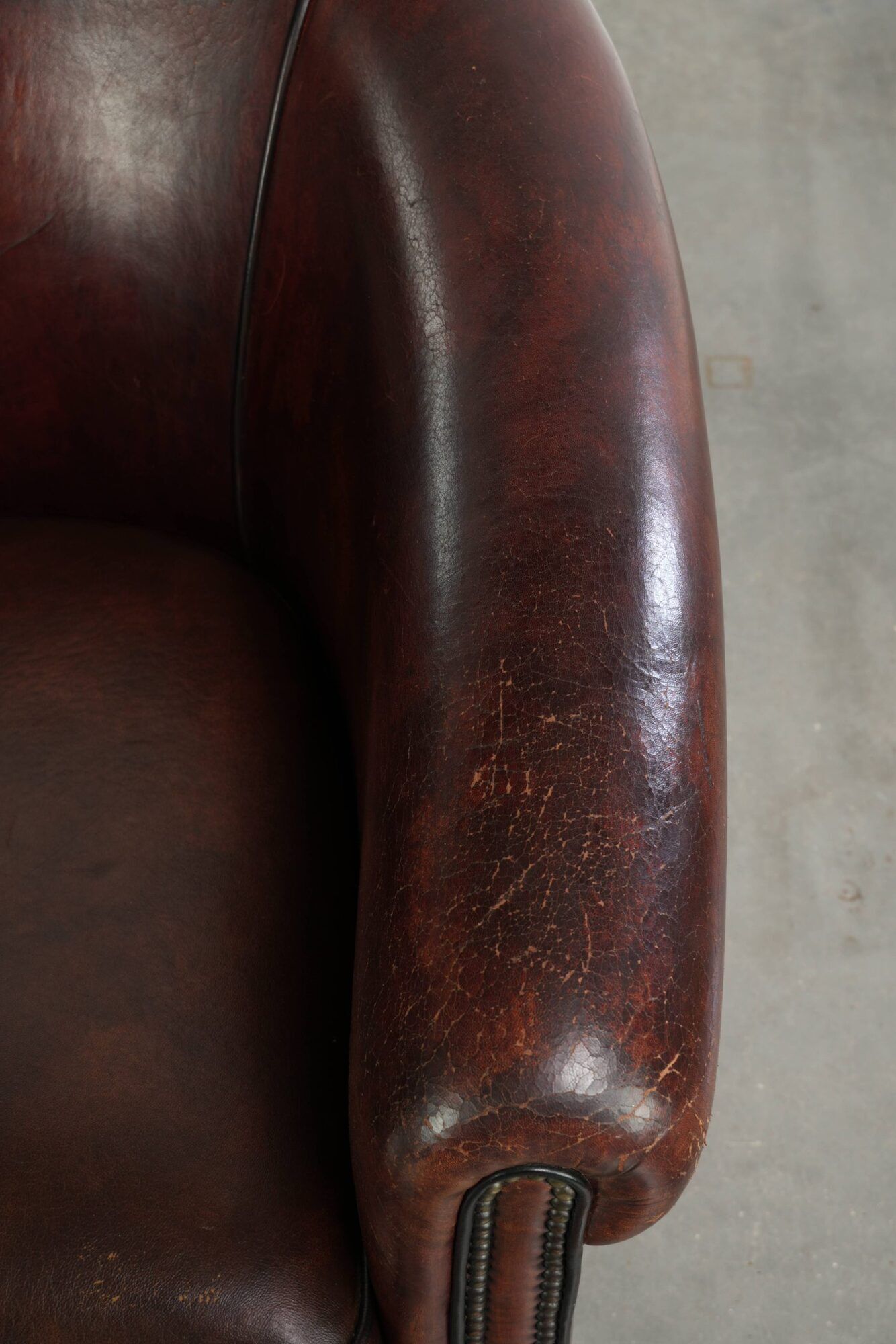Vintage sheepskin club armchair with decorative nails and black piping