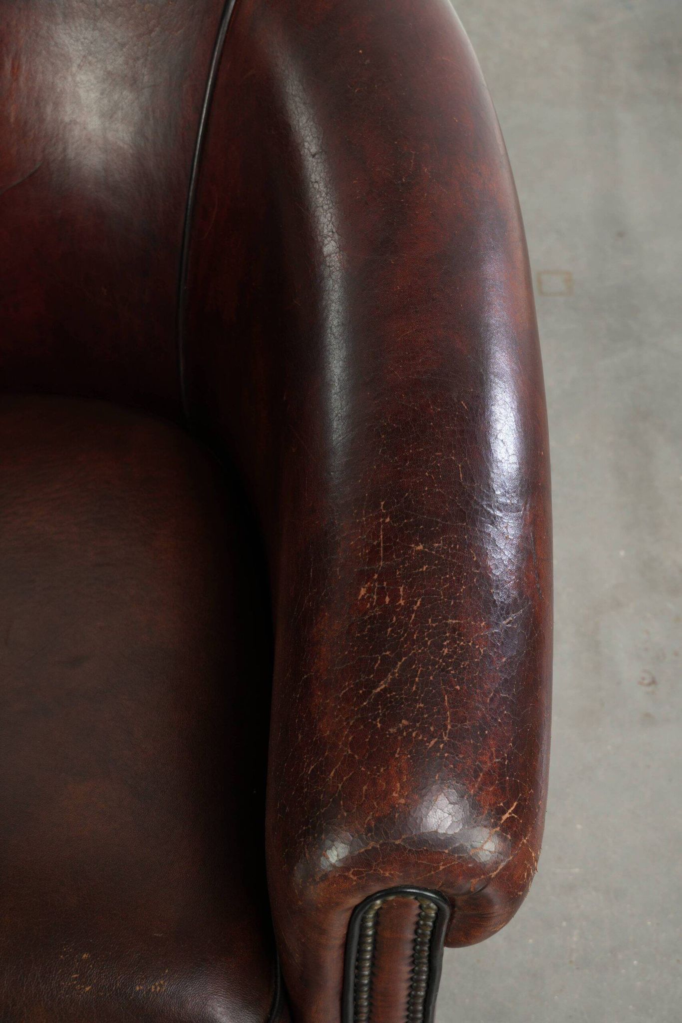 Vintage sheepskin club armchair with decorative nails and black piping