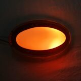 Oval wall lamp with mirror frame. 1980s 18x30cm