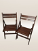 Pair of folding chairs made of dark wood slats.