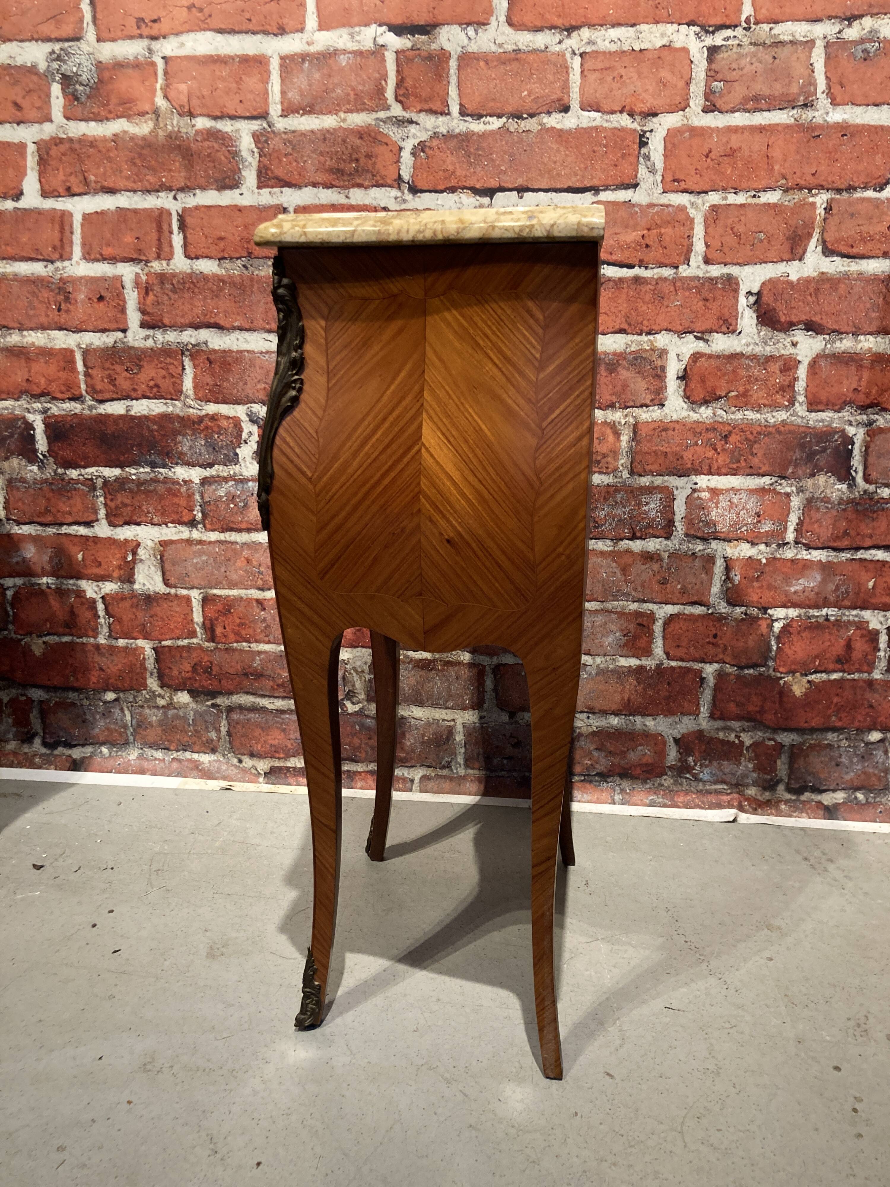 Wooden bedside table topped with a pink marble top