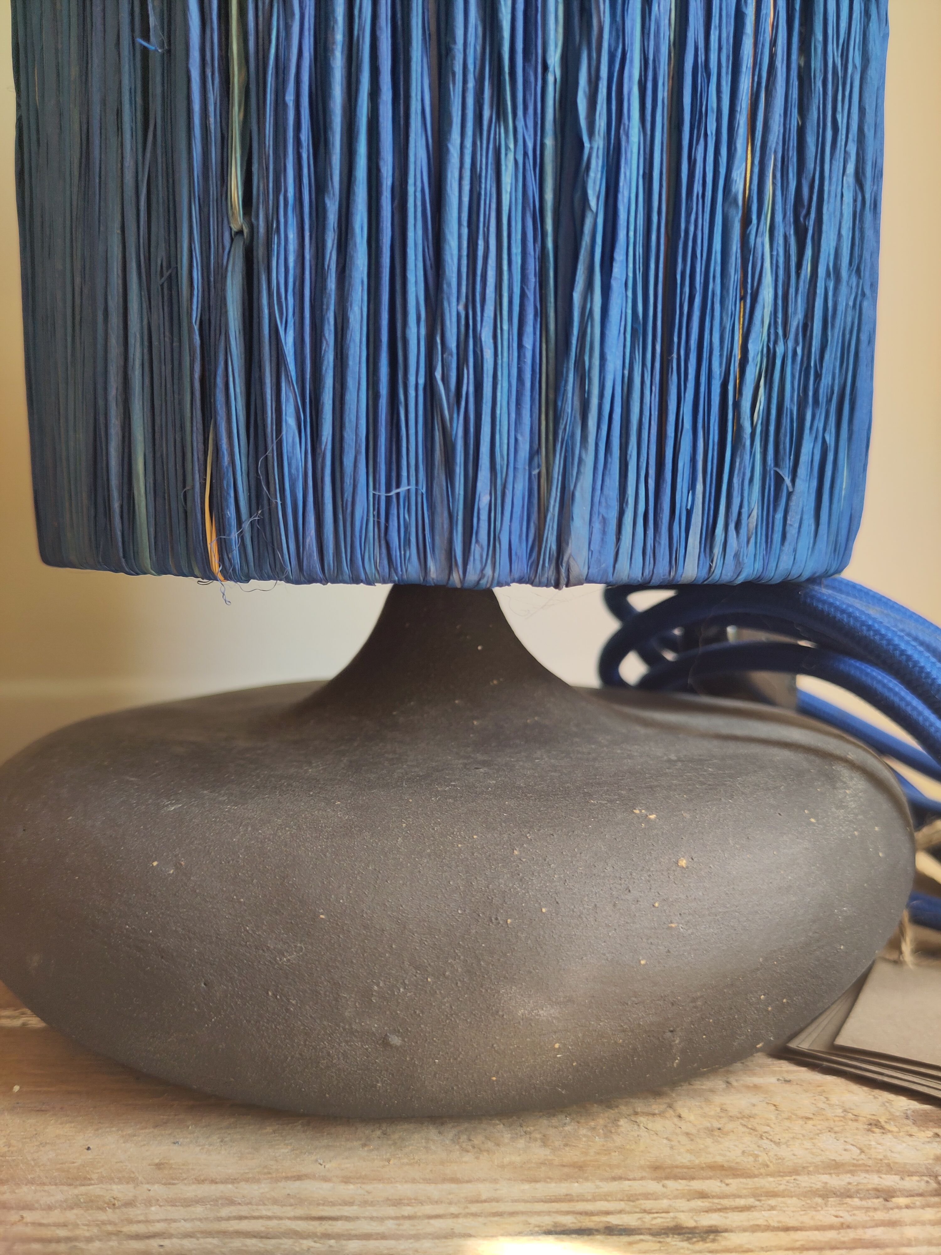 Table lamp in black stoneware and natural raffia.