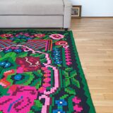 Handwoven colorful Romanian carpet, green and black background with gorgeous colorful flowers