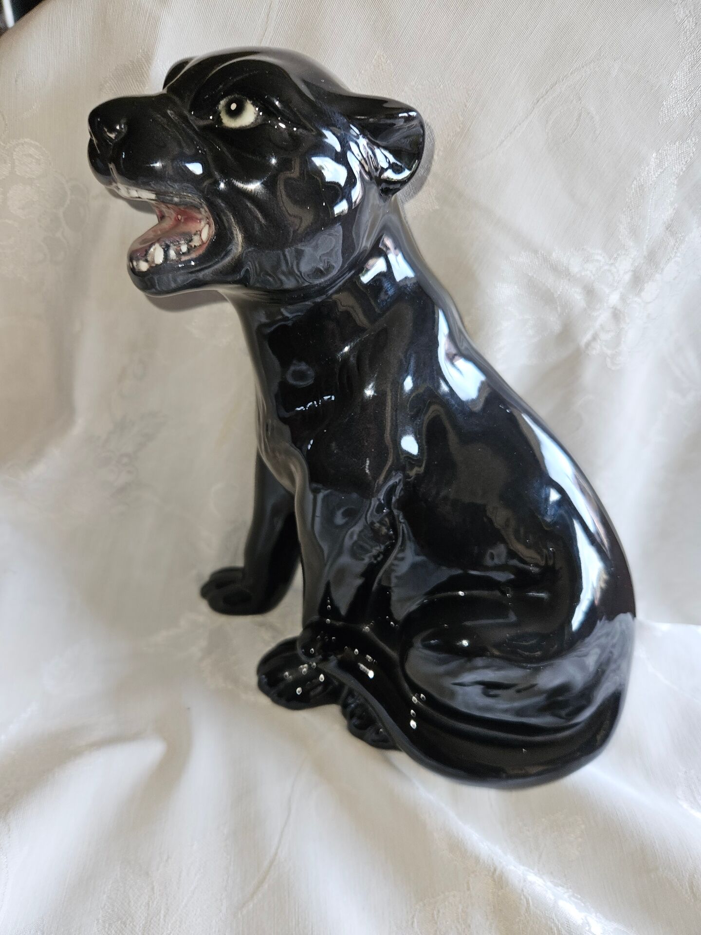 Statue of a roaring panther/leopard sitting in black glazed ceramic.