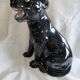 Statue of a roaring panther/leopard sitting in black glazed ceramic.