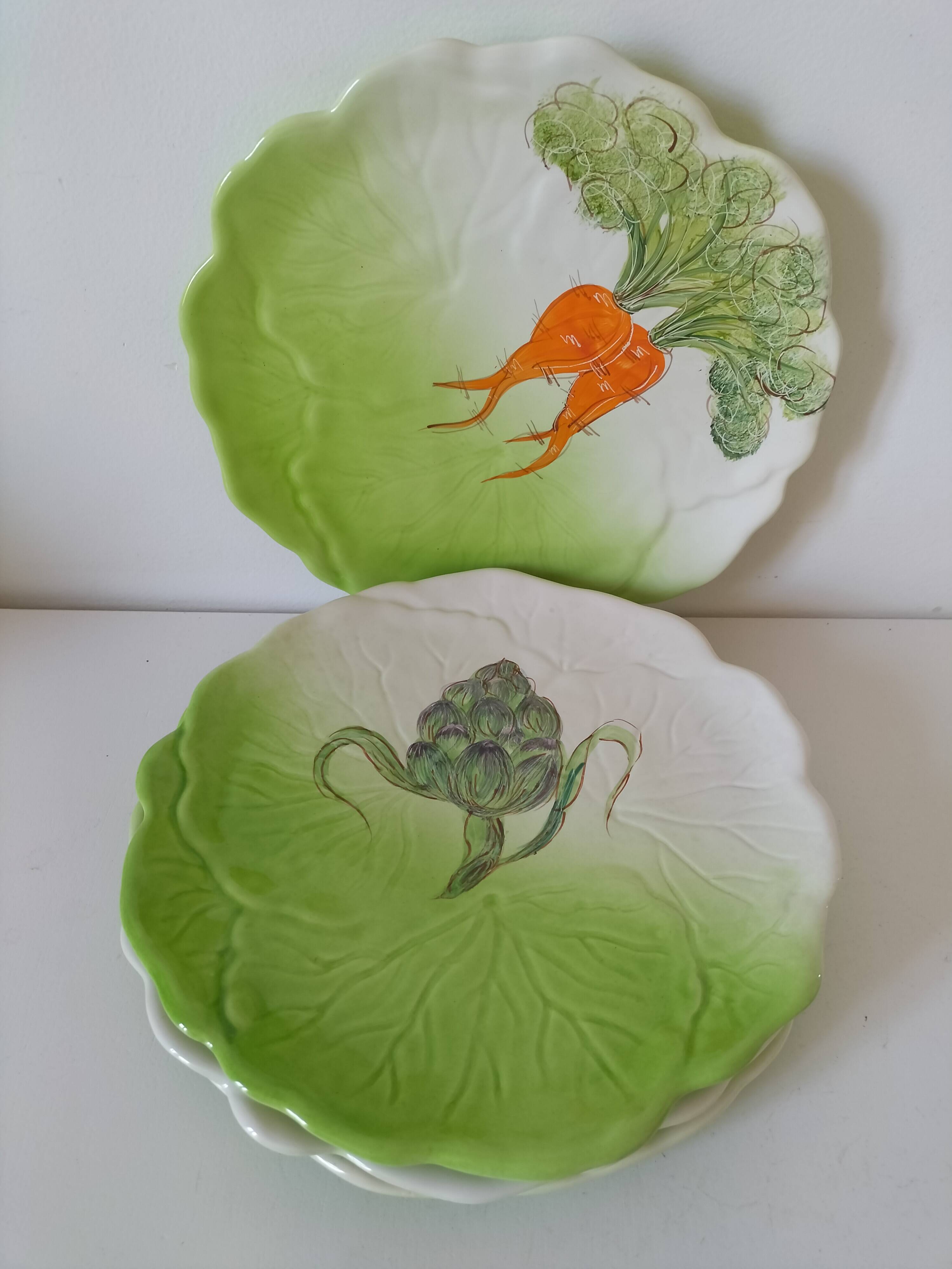 4 hand-decorated earthenware plates with vegetable and green leaf designs.
