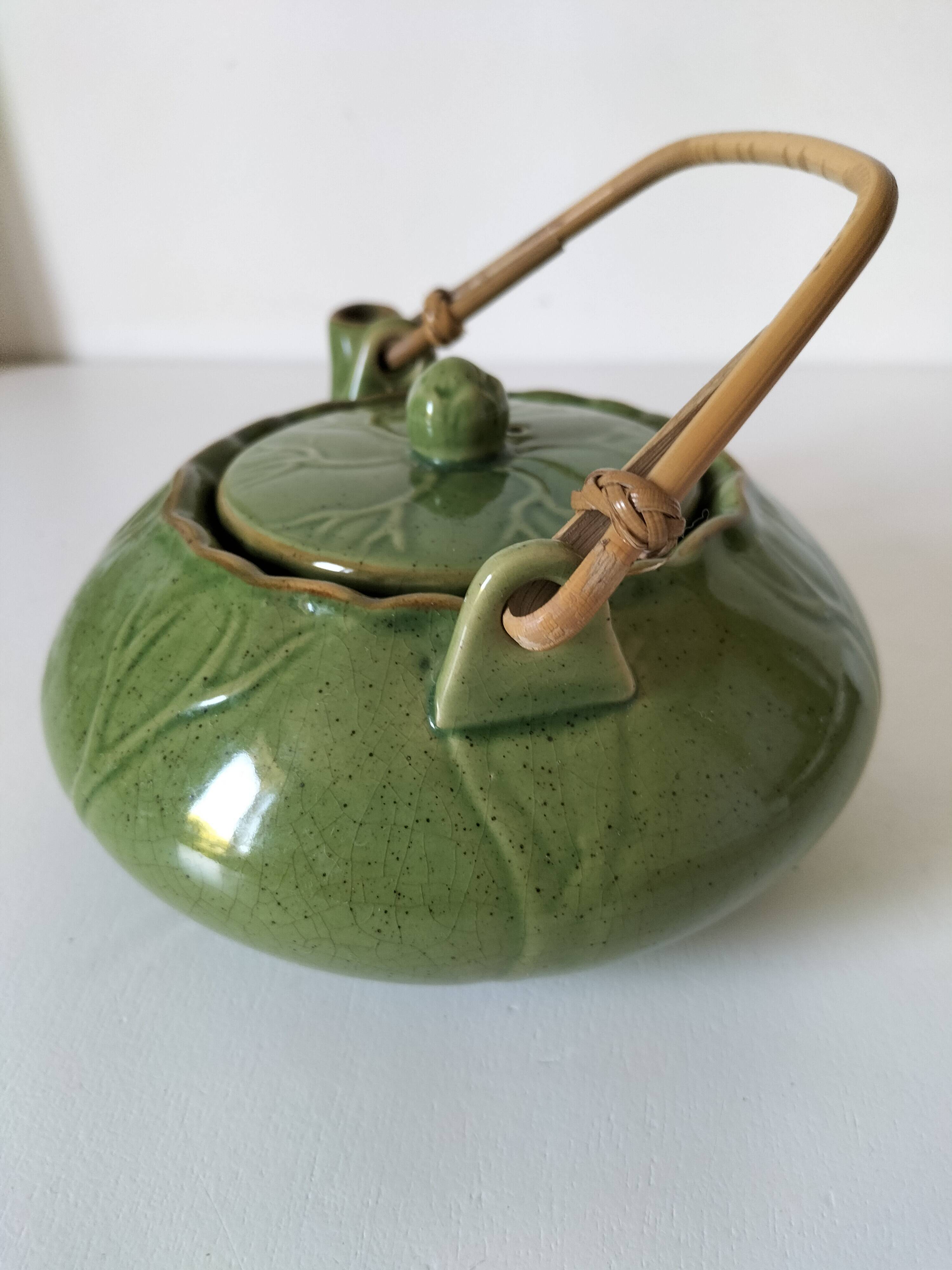 Vintage green teapot with lotus decoration and bamboo handle.