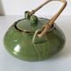 Vintage green teapot with lotus decoration and bamboo handle.