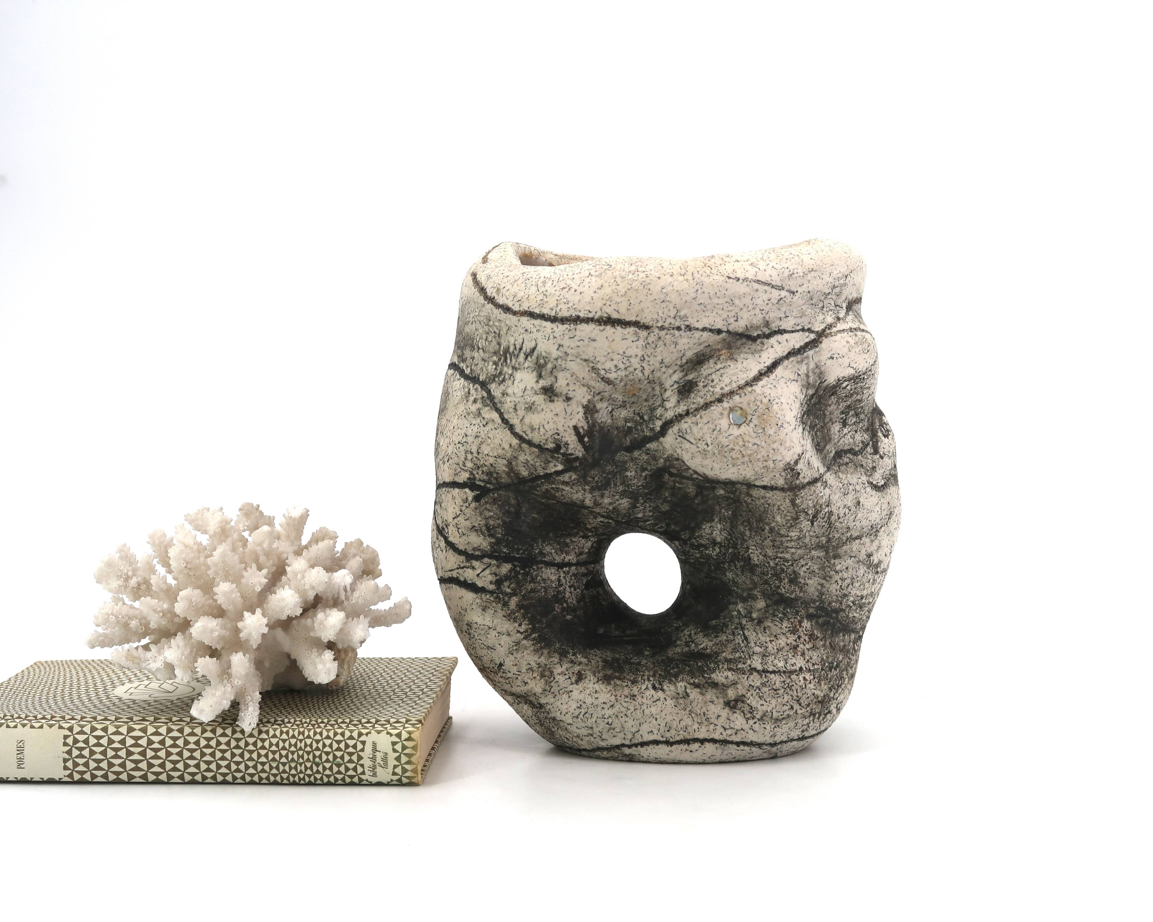 Ceramic vase sculpture decorated with faces and featuring a hole, 1980s.