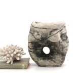 Ceramic vase sculpture decorated with faces and featuring a hole, 1980s.