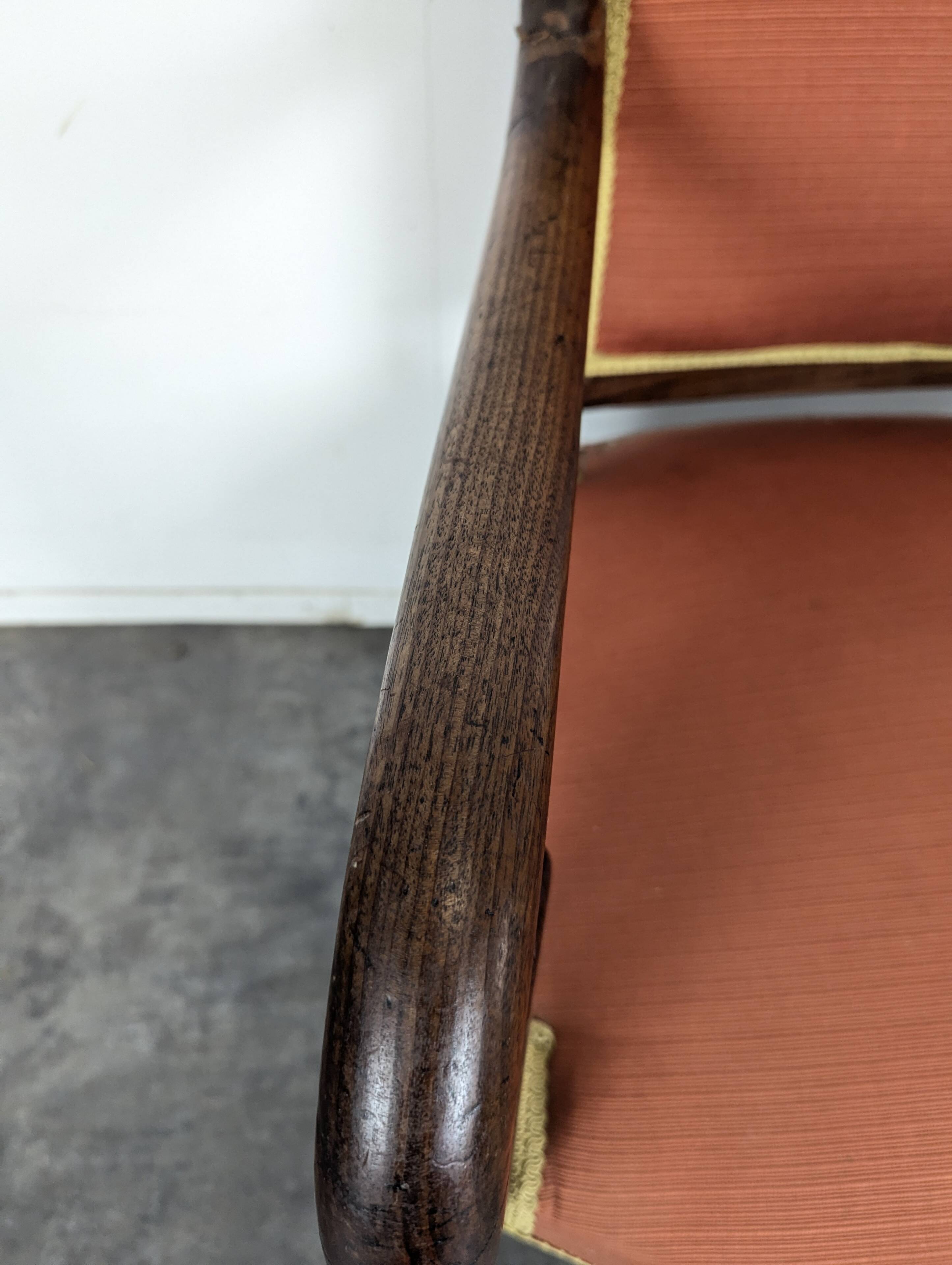 Restoration armchair in mahogany with cross arms and orange fabric.