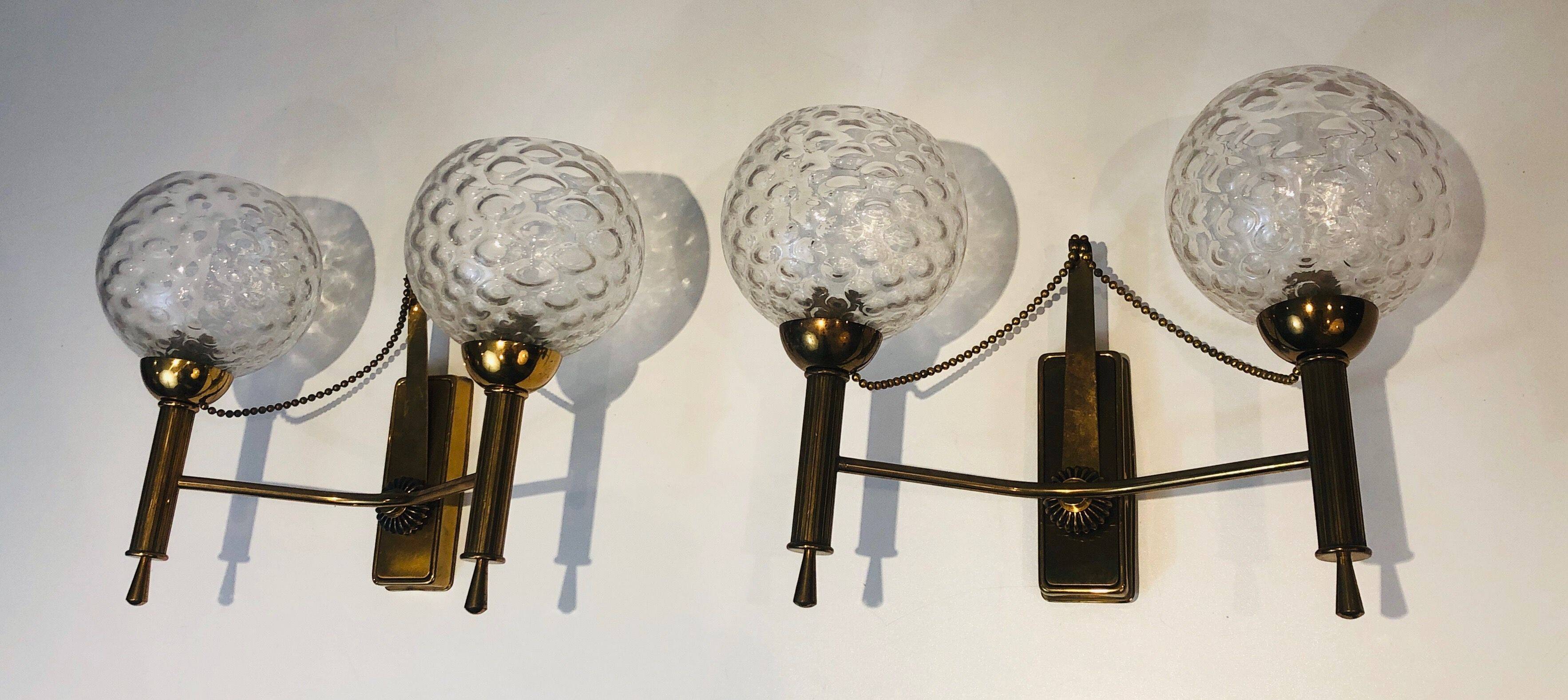 Pair of brass wall lights with glass globes. Around 1970.