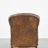 Fauteuil ancien en cuir de mouton sur roulettes et patiné