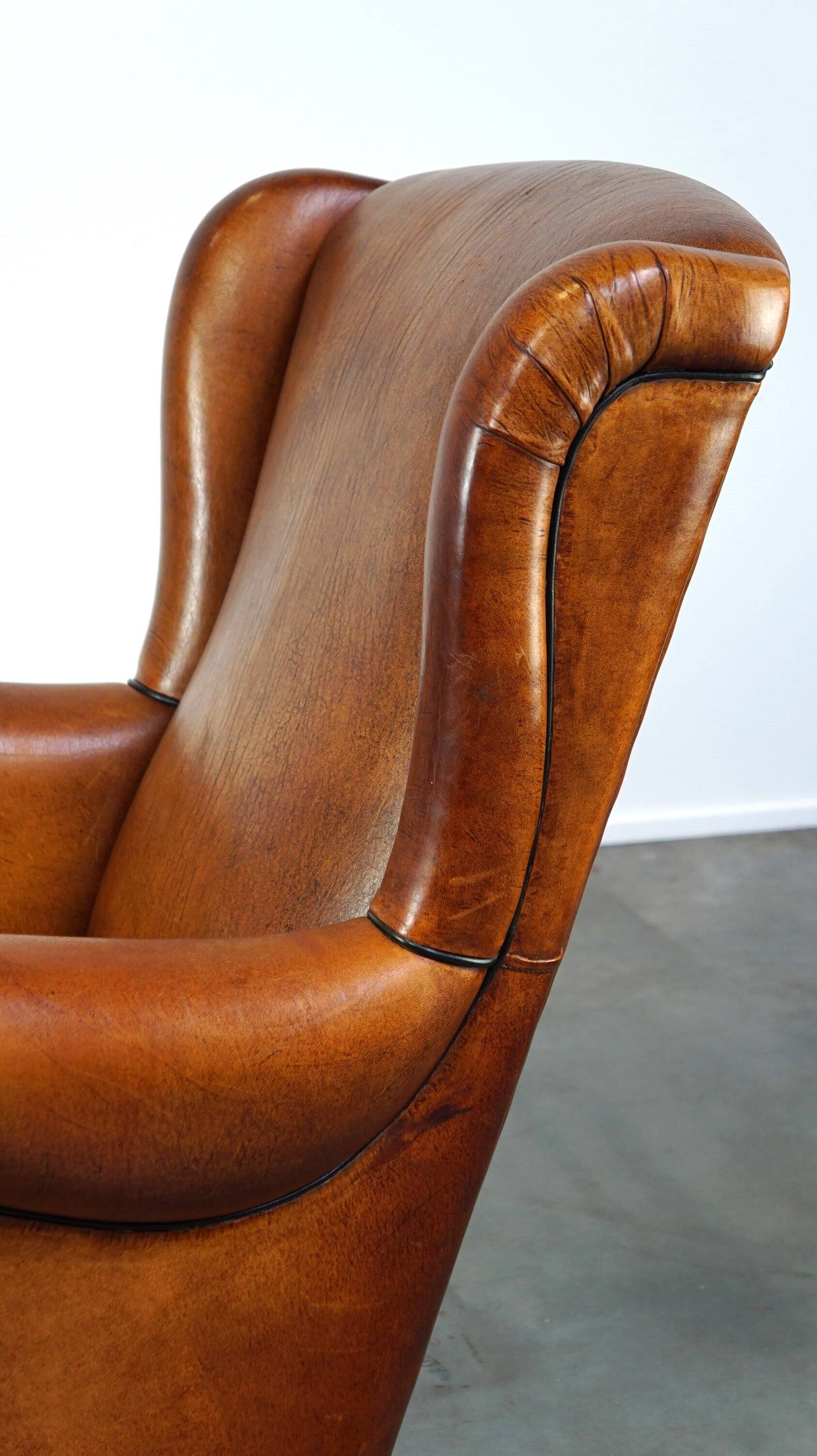 Subtle sheepskin wing chair in good condition on brass front wheels