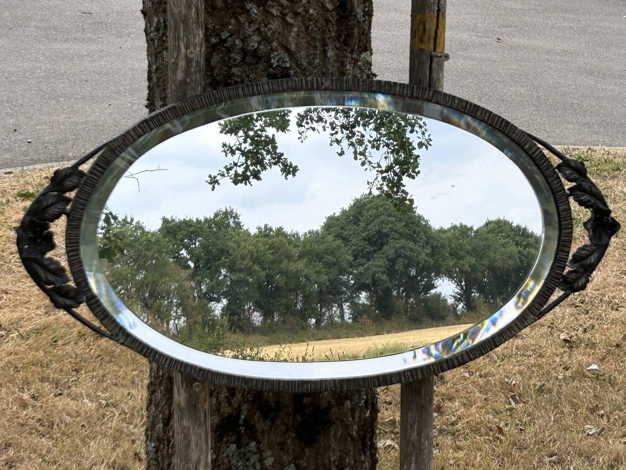 Bevelled oval mirror, richly crafted Art Deco wrought iron.